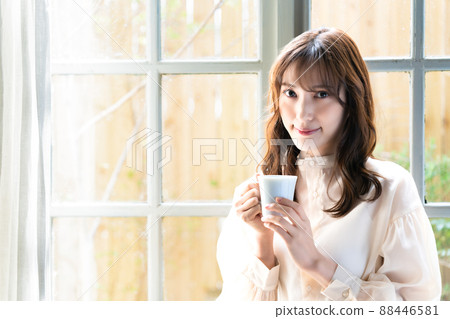 A woman drinking coffee at the window A woman drinking coffee at the window 88446581