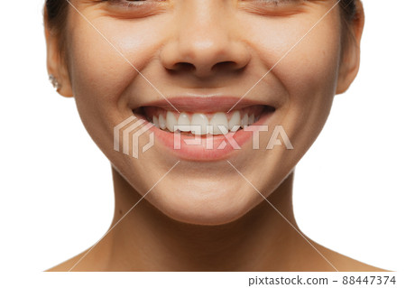 Cropped close-up image of female lips, cheecks and nose isolated over white studio bacground. Perfect healthy smile Cropped close-up image of female lips, cheecks and nose isolated over white studio bacground. Perfect healthy smile 88447374