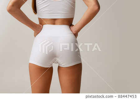 Sportive bottocks, legs. Cropped image of female body in white uderwear isolated over gray studio background 88447453