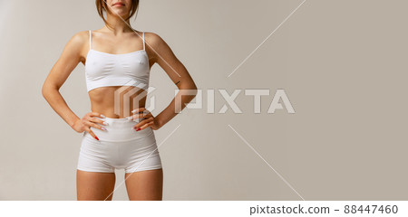 Cropped portrait of sportive slim female body in white cotton underwear posing isolated over gray studio background. Flyer 88447460
