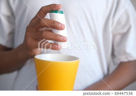 young man putting artificial sweetener in tea, 88447536