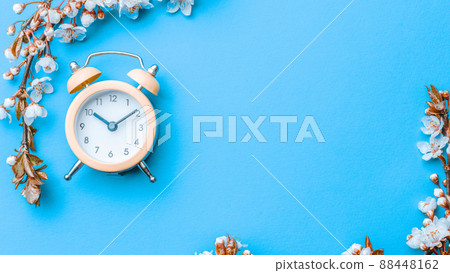 Spring background blue with flower blossom and April floral nature in beautiful scene with blooming tree, alarm clock . Easter Sunny day. Orchard abstract blurred background. Springtime. 88448162