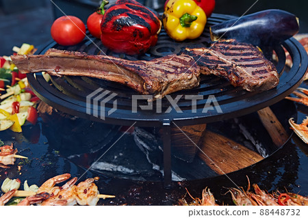 Tomahawk rib beef steak and T-bone on hot black grill. Tomahawk rib beef steak and T-bone on hot black grill. 88448732