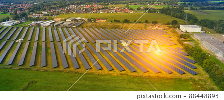 Aerial view of a large solar plant with solar panels and sun reflexions on the edge of a village in Germany Aerial view of a large solar plant with solar panels and sun reflexions on the edge of a village in Germany 88448893