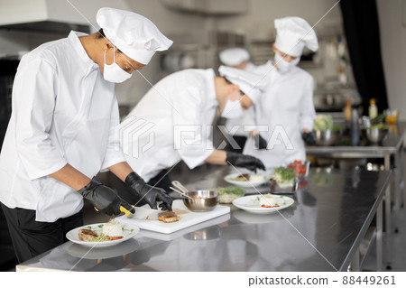 al group of cooks finishing main courses while working together in the kitchen 88449261