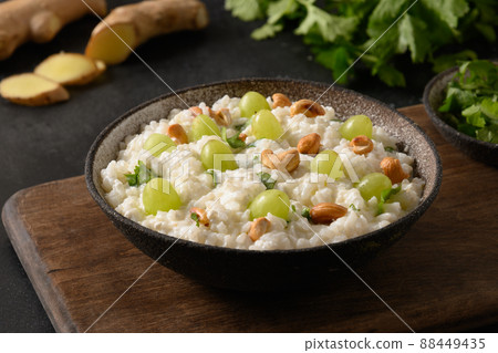 Curd Rice with cashews, grapes, cilantro, ginger on a black background. Indian cuisine Curd Rice with cashews, grapes, cilantro, ginger on a black background. Indian cuisine 88449435