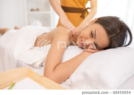 In a spa salon, a young woman enjoys massage therapy. 88450954