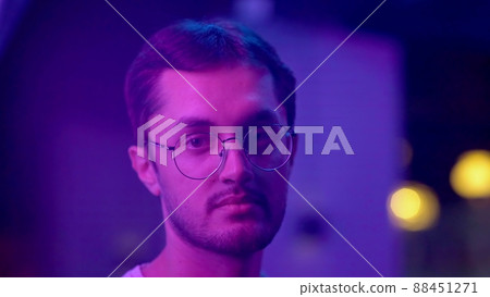 Close-up of a young man looking into the camera under a neon light. Night club 88451271