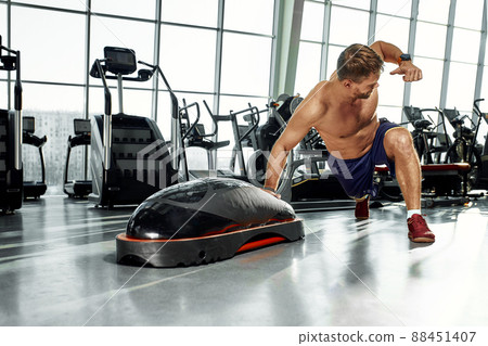 Handsome muscular men works out on functional training soft platform in gym. Handsome muscular men works out on functional training soft platform in gym. 88451407