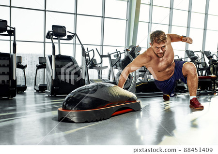 Handsome muscular men works out on functional training soft platform in gym. Handsome muscular men works out on functional training soft platform in gym. 88451409