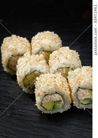 Traditional delicious fresh sushi roll set on a black background. Sushi roll with rice, cream cheese, avocado, salmon, sesame. Philadelphia. Sushi menu. Japanese kitchen, restaurant. 88451461
