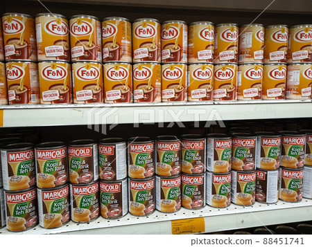 SELANGOR, MALAYSIA -APRIL 4, 2022: Sweetened creamer and evaporated milk packed in cans. Displayed for sale on the rack inside the supermarket. The main ingredient is made from palm oil seeds. 88451741