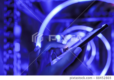 Woman using smartphone at exhibition with blue illumination - close up view 88452803