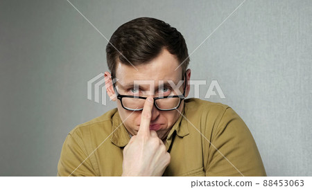 Emotional man with bad eyesight adjusts black-rimmed glasses 88453063