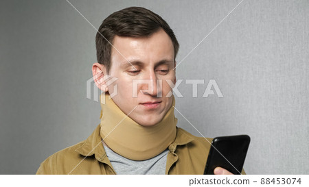 Man with bandage on neck checks social networks via phone Man with bandage on neck checks social networks via phone 88453074