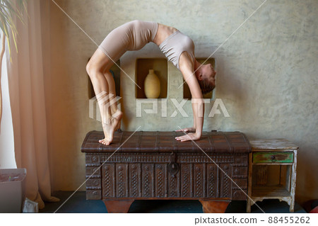A beautiful and slender woman in a beige top and breeches, stands in a yoga pose, performs the exercise bridge A beautiful and slender woman in a beige top and breeches, stands in a yoga pose, performs the exercise bridge 88455262