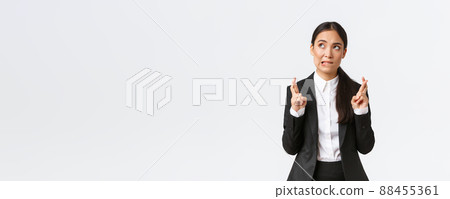 Hopeful asian businesswoman looking worried, biting lip and cross fingers good luck, making wish, anticipating big contract or deal, worried about outcome, standing white background Hopeful asian businesswoman looking worried, biting lip and cross fingers good luck, making wish, anticipating big contract or deal, worried about outcome, standing white background 88455361