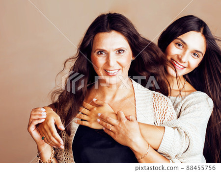 cute pretty teen daughter with mature mother hugging, fashion style brunette makeup together, warm colors cute pretty teen daughter with mature mother hugging, fashion style brunette makeup together, warm colors 88455756