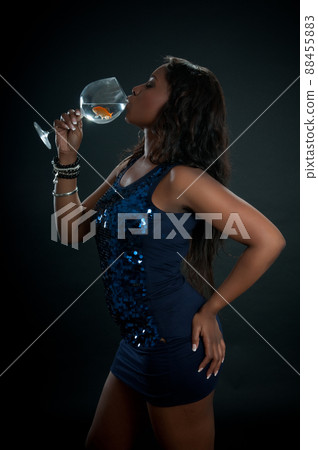 African American woman drinking from a glass with water with a fish inside African American woman drinking from a glass with water with a fish inside 88455883
