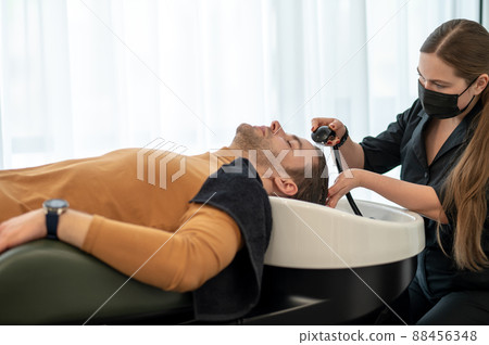 Female hairdresser washing hair to the customer Female hairdresser washing hair to the customer 88456348