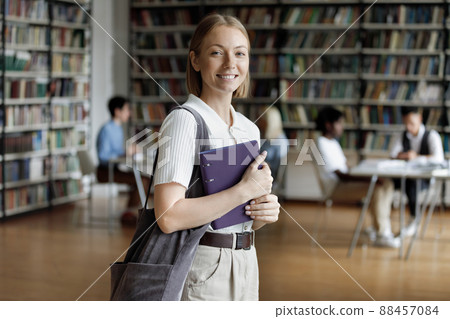 Beautiful smiling teen girl posing in university library Beautiful smiling teen girl posing in university library 88457084
