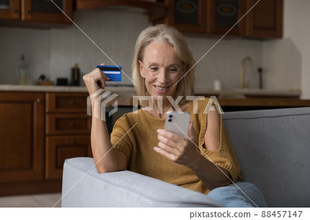 Happy mature customer lady using credit card, mobile phone Happy mature customer lady using credit card, mobile phone 88457147