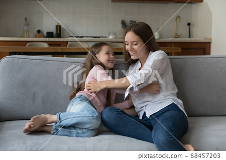 Happy playful mom tickling excited daughter girl on sofa 88457203