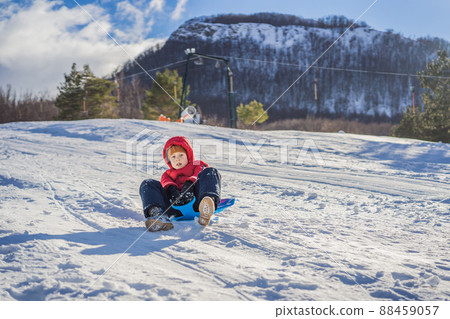 happy and positive little boy enjoying sledding and cold weather outdoor, winter fun activity concept happy and positive little boy enjoying sledding and cold weather outdoor, winter fun activity concept 88459057
