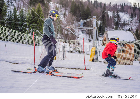 Boy learning to ski, training and listening to his ski instructor on the slope in winter 88459207