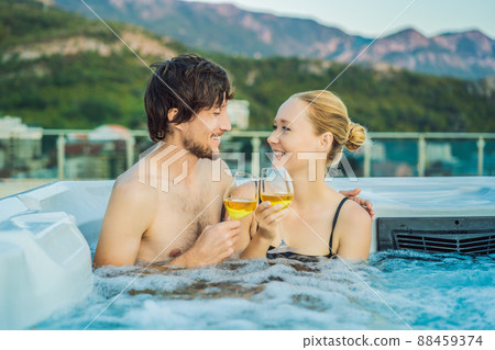Portrait of young carefree happy smiling couple relaxing at hot tub during enjoying happy traveling moment vacation life against the background of green big mountains 88459374