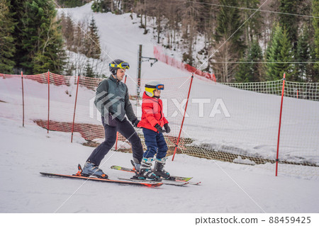 Boy learning to ski, training and listening to his ski instructor on the slope in winter Boy learning to ski, training and listening to his ski instructor on the slope in winter 88459425