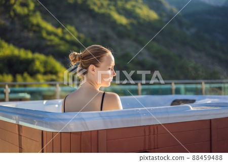 Portrait of young carefree happy smiling woman relaxing at hot tub during enjoying happy traveling moment vacation life against the background of green big mountains Portrait of young carefree happy smiling woman relaxing at hot tub during enjoying happy traveling moment vacation life against the background of green big mountains 88459488