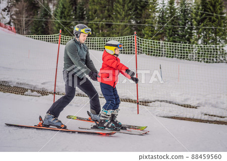 Boy learning to ski, training and listening to his ski instructor on the slope in winter Boy learning to ski, training and listening to his ski instructor on the slope in winter 88459560