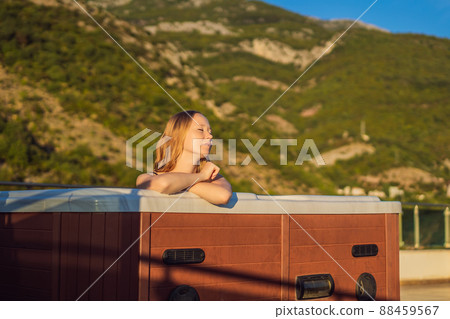 Portrait of young carefree happy smiling woman relaxing at hot tub during enjoying happy traveling moment vacation life against the background of green big mountains Portrait of young carefree happy smiling woman relaxing at hot tub during enjoying happy traveling moment vacation life against the background of green big mountains 88459567