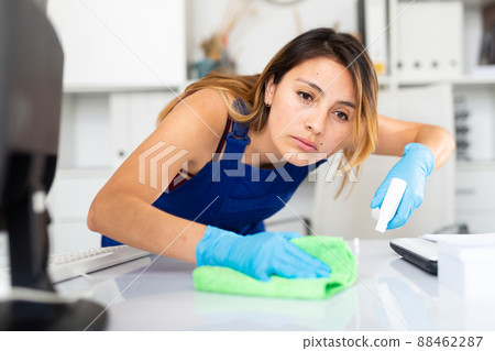 Mexican woman wearing uniform cleaning table in office 88462287