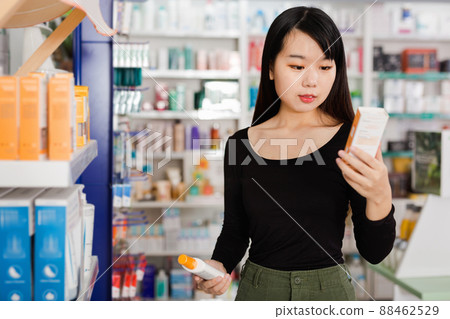 Young chinese female customer looking for right medicine in pharmaceutical store Young chinese female customer looking for right medicine in pharmaceutical store 88462529