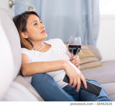 Latino woman relaxing at evening with glass of red wine Latino woman relaxing at evening with glass of red wine 88462626