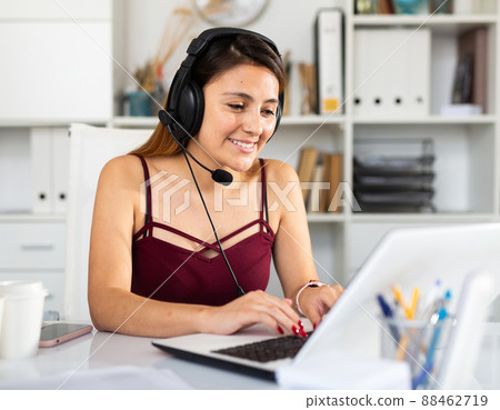 Young woman call centre operator with headphones in office Young woman call centre operator with headphones in office 88462719