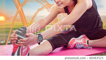 Mid section of caucasian female athlete stretching her leg against light trails Mid section of caucasian female athlete stretching her leg against light trails 88463525