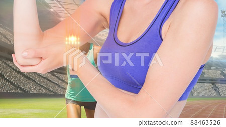 Light spot against mid section of caucasian female athlete holding her injured elbow on sports track Light spot against mid section of caucasian female athlete holding her injured elbow on sports track 88463526