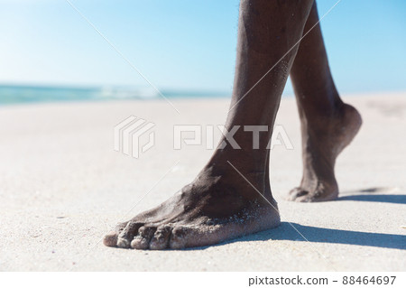 Low section of african american senior man walking barefoot on sand at beach during sunny day Low section of african american senior man walking barefoot on sand at beach during sunny day 88464697