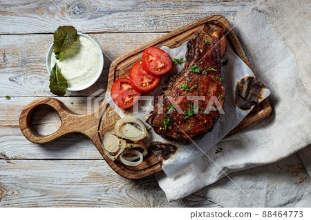 Grilled steak. Appetizing roasted meat with vegetables and herbs. Top view. Copy space. Rustic wooden table background. Grilled steak. Appetizing roasted meat with vegetables and herbs. Top view. Copy space. Rustic wooden table background. 88464773