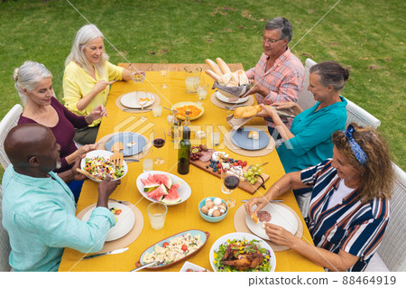High angle view of multiracial senior friends enjoying food at table during backyard party 88464919