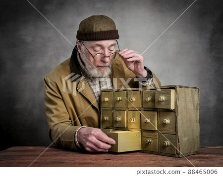 bearded senior man with antique apothecary cabinet 88465006