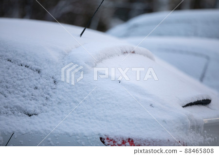 A car covered in a thin layer of snow during winter weather. 88465808