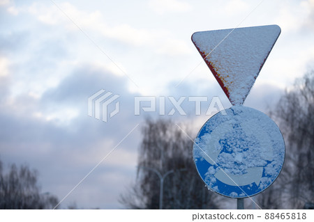 Snowy road sign, intersection with circular traffic. 88465818