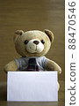 Portrait portrait brown teddy bears and white blank paper on brown wooden background. Birthday or anniversary card concept. 88470546