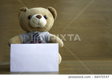 Brown teddy bears and white blank paper on brown wooden background. Birthday or anniversary greeting card concept. Brown teddy bears and white blank paper on brown wooden background. Birthday or anniversary greeting card concept. 88470547