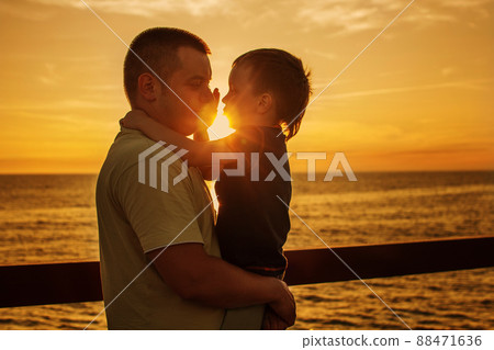 Dad and son playing at the pier on the sea at sunset Dad and son playing at the pier on the sea at sunset 88471636