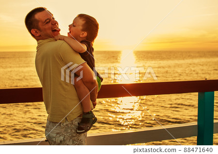 Dad and son playing at the pier on the sea at sunset Dad and son playing at the pier on the sea at sunset 88471640